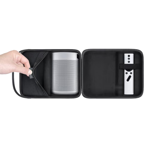 A black hard-shell carrying case shown open on a white background, with a hand opening a side flap. Inside, a silver cylindrical projector is secured on the left side and a white remote control is stored on the right side.