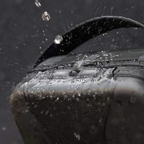 Close-up of a black waterproof Xgimi Projector bag with water droplets splashing off its surface and handle, demonstrating its water-resistant properties.