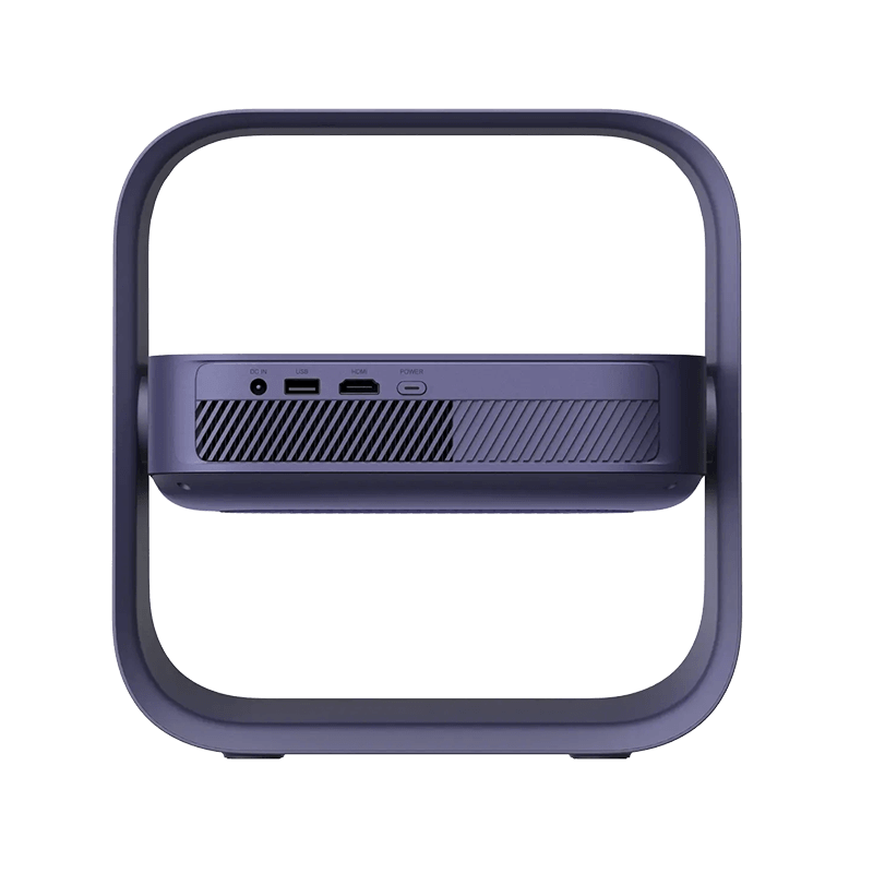 A modern, minimalist projector or media player shown from the back, featuring a dark slate blue body with a large, integrated square stand. The back panel includes ventilation grilles and several port icons (USB-C, USB, HDMI, audio jack).
